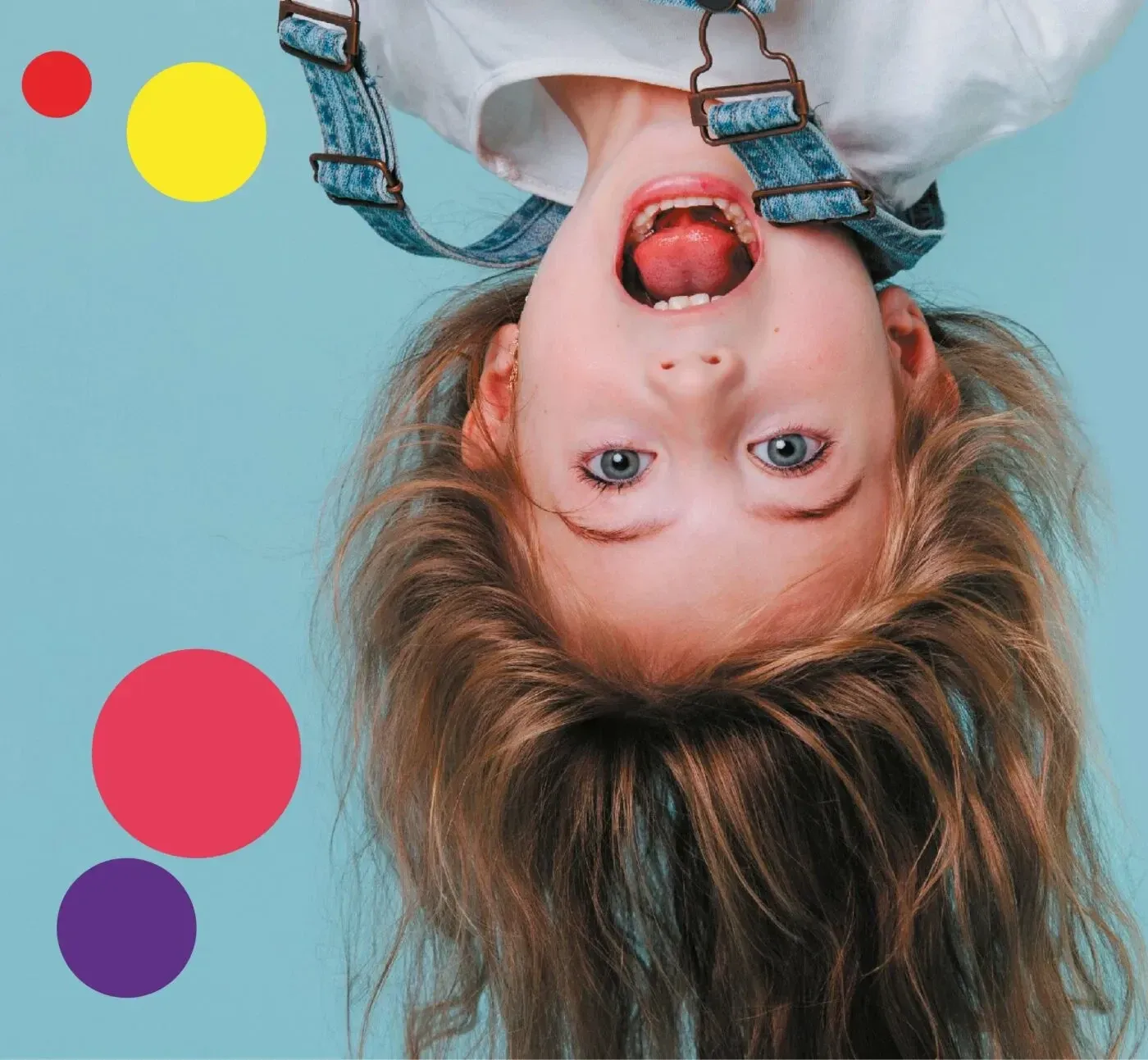 A happy kid upside down — because haircuts at Snip Snap are an adventure