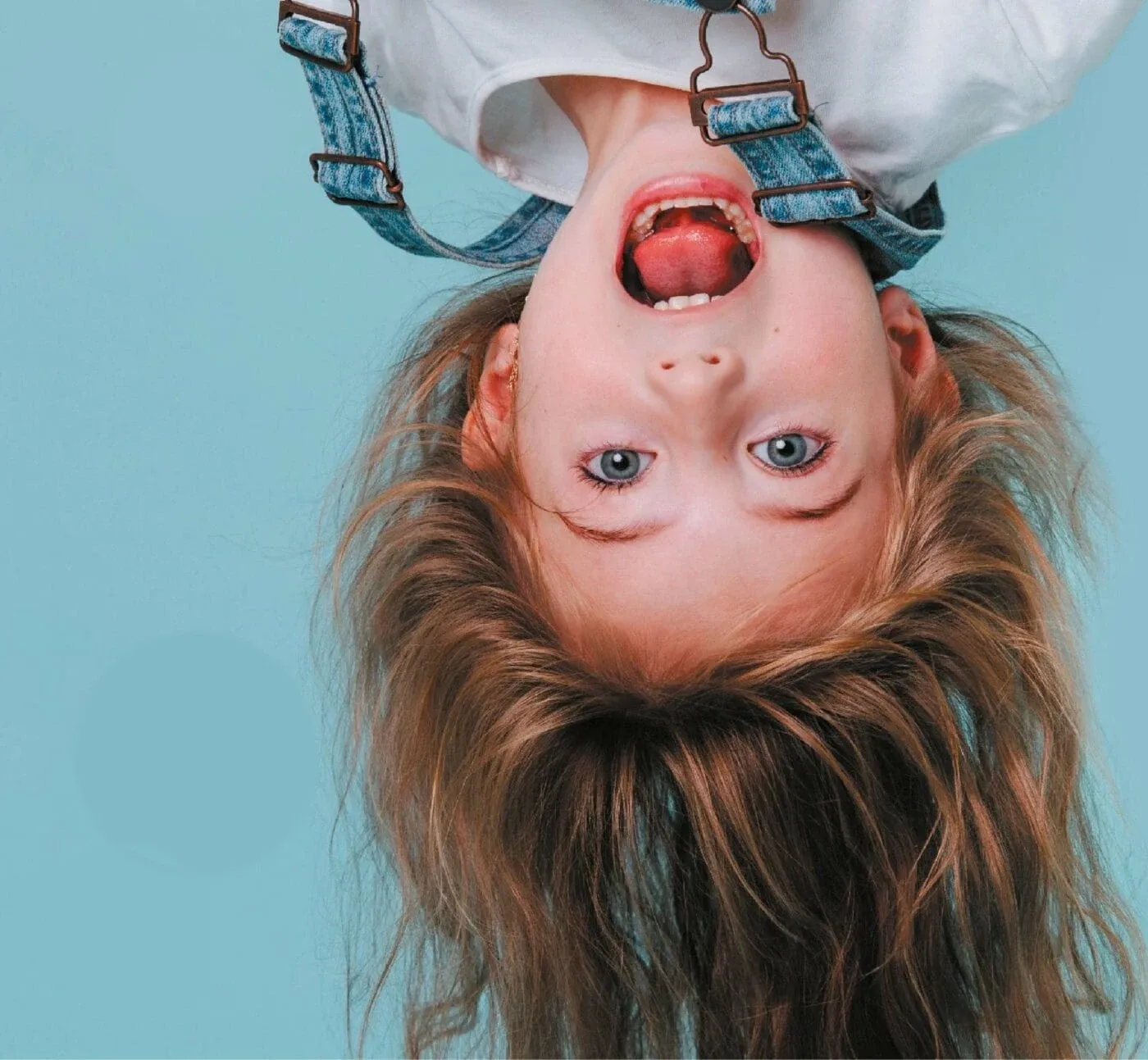 A happy kid upside down — because haircuts at Snip Snap are an adventure